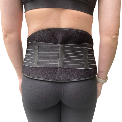 Pregnant woman putting on pregnancy pelvic belt for pelvic girdle pain