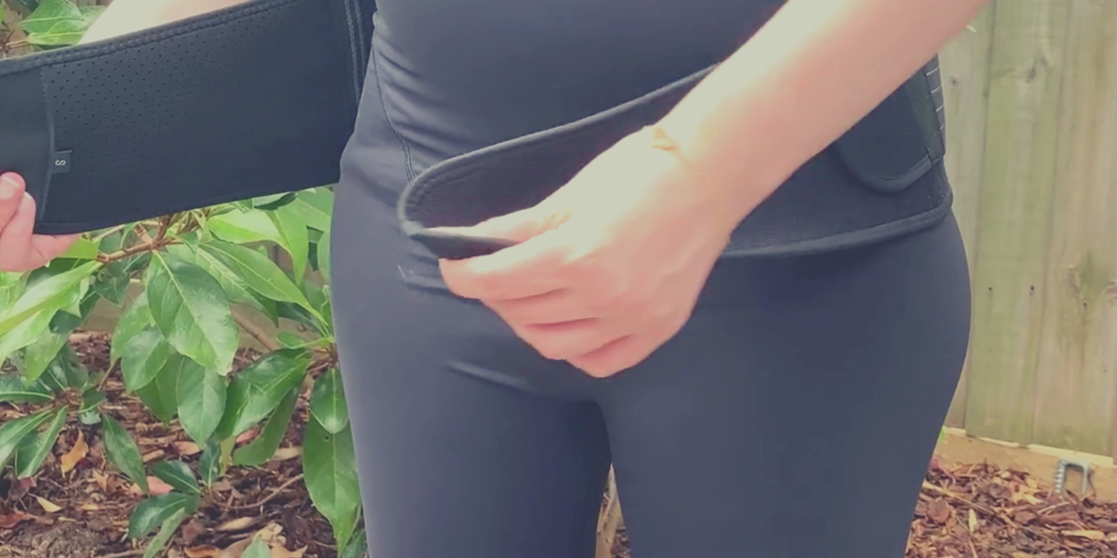 Load video: Pregnant woman putting on GRDL pregnancy pelvic belt in black colour, using supportive straps.